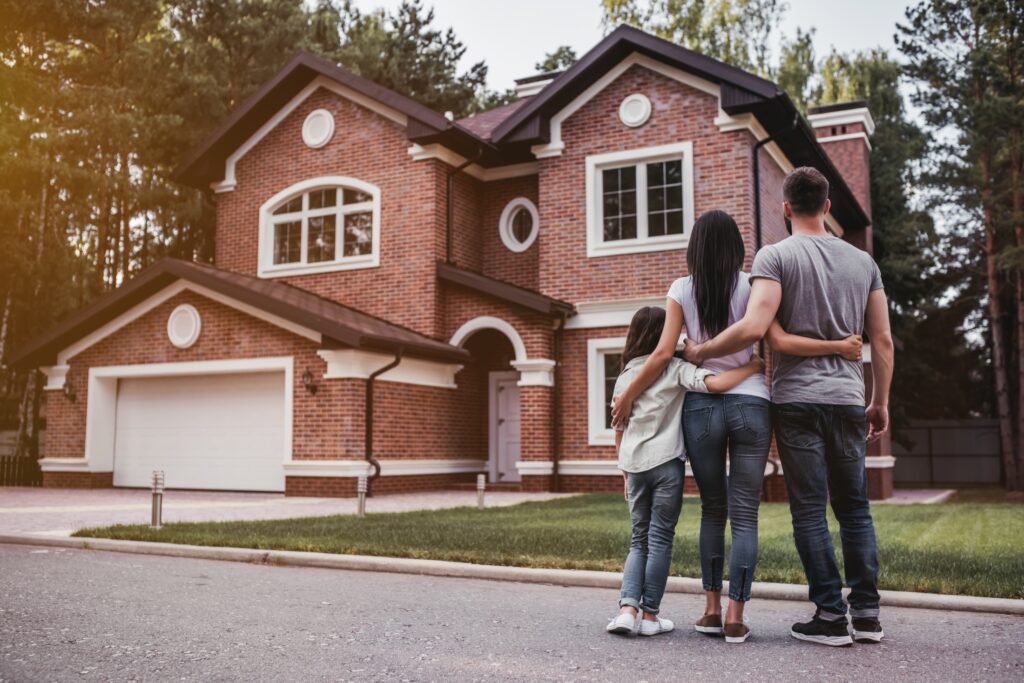 Back view of happy family is standing near their modern house and hugging